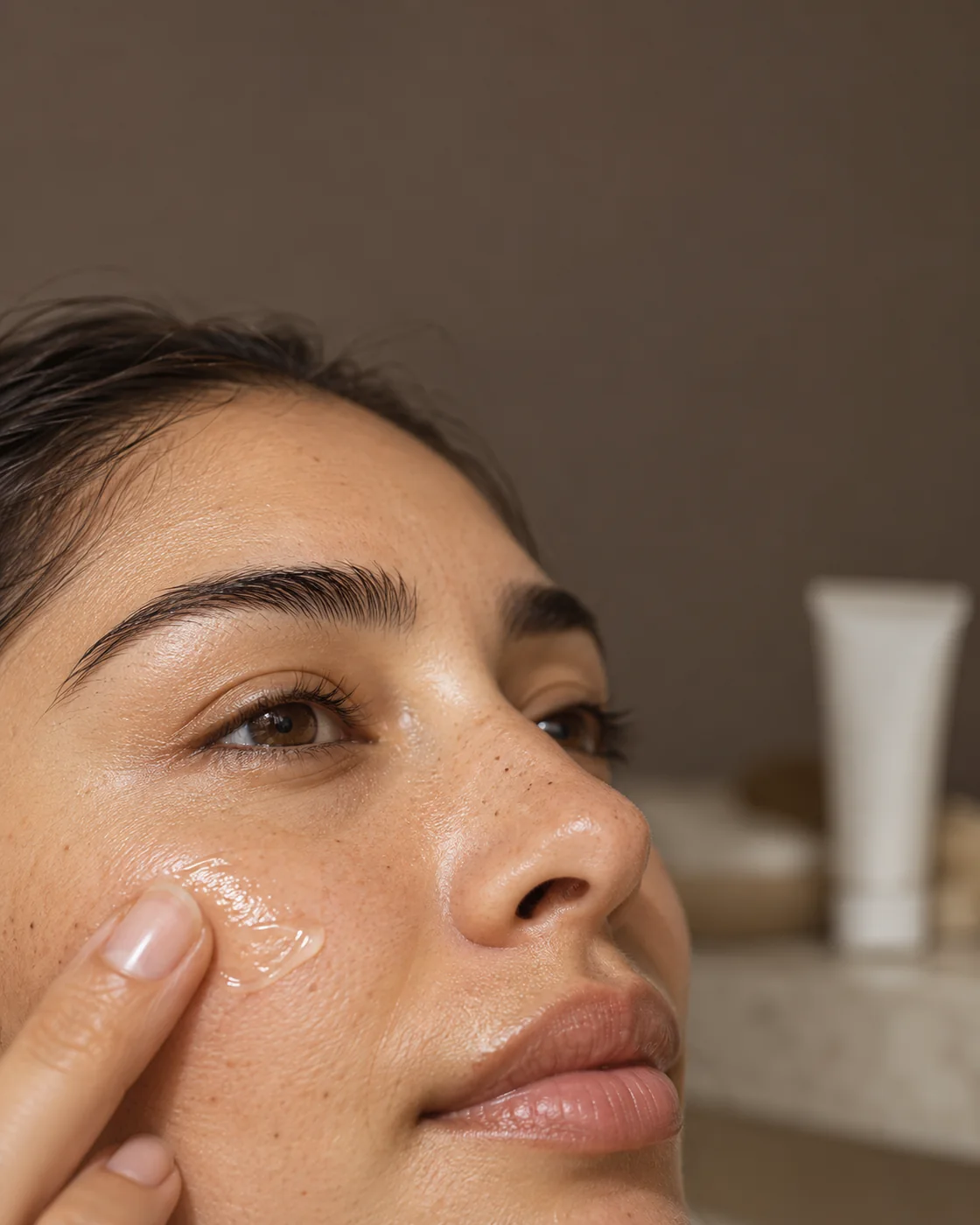 Application douce d’un soin facial transparent près du nez, illustration d’un geste sans marque de produit